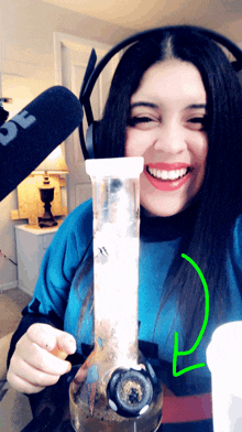 a woman wearing headphones is smiling while holding a bong in her hand