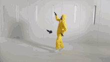 a man in a yellow protective suit is dancing in a room