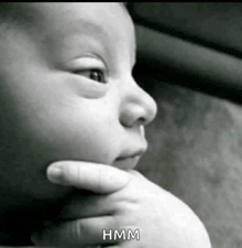 a black and white photo of a baby 's face with hmm written on the bottom