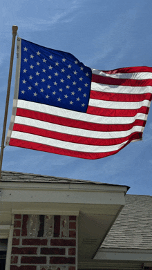 a large american flag is flying over a brick house