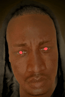 a man with red eyes is wearing a black hood