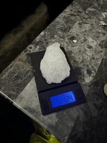 a digital scale displays the weight of a piece of ice at 12.4 grams