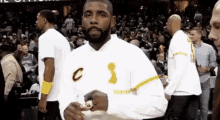 a man with a beard is standing in front of a crowd on a basketball court holding a trophy .