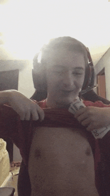 a man wearing headphones is taking off his shirt and holding a 20 dollar bill