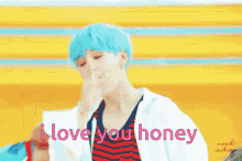 a boy with blue hair is dancing in front of a yellow background with the words `` i love you honey '' written on it .