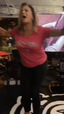 a woman wearing a pink georgia shirt is dancing