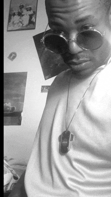 a black and white photo of a man wearing sunglasses and a pendant that says a2bp