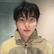 a young man with a bandage on his face is wearing a jacket