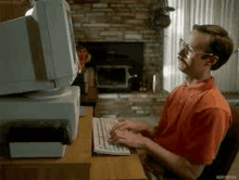 a man is sitting at a desk typing on a keyboard in front of a computer .