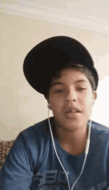 a young boy wearing a black hat and ear buds looks at the camera