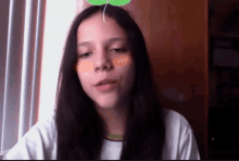 a young girl with a green leaf on her head looks at the camera