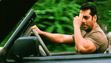 a man is driving a car on a road and making a funny face .