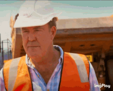 a man wearing an orange vest and a white hard hat has the word imgplay on the bottom