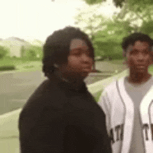 two young men are standing next to each other on a sidewalk .