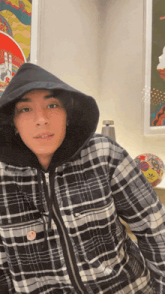 a man wearing a plaid shirt and a hooded jacket