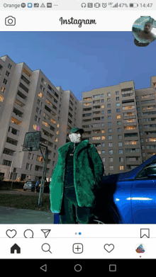 a man in a green fur coat is standing in front of a blue car in an instagram photo