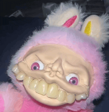 a pink stuffed animal with bunny ears and big teeth looks at the camera