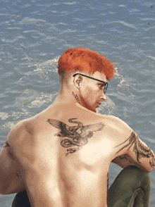 a man with red hair has a tattoo on his back of a bird and a snake