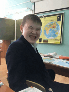 a boy making a funny face in front of a map of the earth