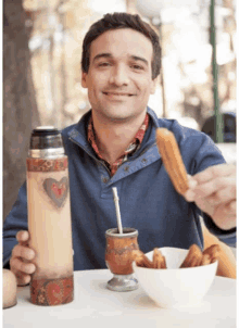 a man sitting at a table with a bowl of food and a thermos with a heart on it