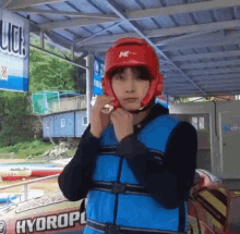 a man wearing a life vest and a red helmet is standing in front of a sign that says hydroplane