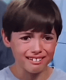 a young boy is making a funny face with his mouth open and his teeth missing .