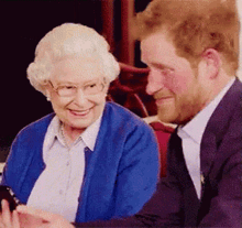 a man and a woman are sitting next to each other and the woman is wearing glasses and a blue cardigan .