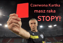 a man holds up a red card with the words czerwona kartka masz raka stopy on the bottom