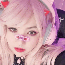 a girl with pink hair is wearing headphones and a cat ear headband .