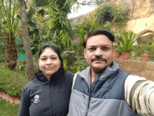 a man and a woman pose for a selfie in front of trees