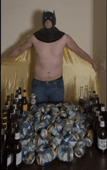 a man in a batman costume stands in front of a table full of beer cans and bottles