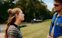 a man and a woman are standing next to each other in a field with a truck in the background