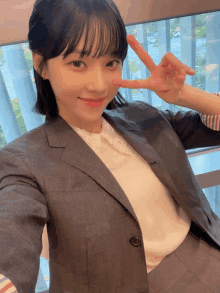 a woman in a suit and white shirt is making a peace sign