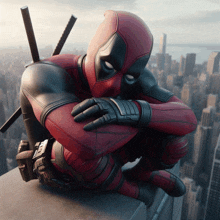 a man in a deadpool costume is sitting on a ledge overlooking a city