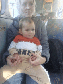 a woman is holding a baby who is wearing a shirt that says nike