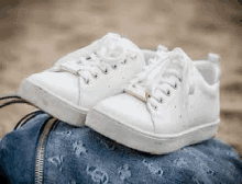 a pair of white sneakers are sitting on top of a blue purse .