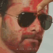 a close up of a man wearing sunglasses and a red face paint .