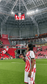 a soccer player wearing number 29 stands in front of a scoreboard