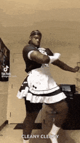 a man is wearing a maid dress and apron and dancing in a room .