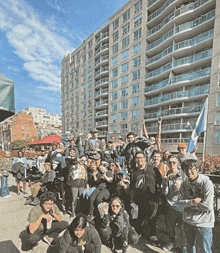 a group of people posing in front of a tall building