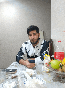 a man is sitting at a table with a bottle of coca cola in front of him