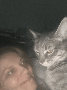 a close up of a woman and a cat with a dark background