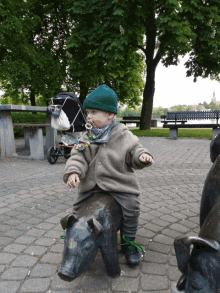 a little boy is sitting on a statue of a pig