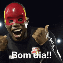 a man wearing a red and yellow mask giving a thumbs up and the words bom dia on the bottom