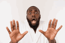 a man in a bathrobe is making a surprised face with his hands up