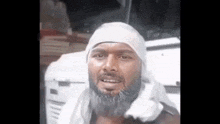 a man with a bandage on his head is standing in front of a white vehicle .