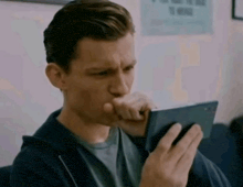 a man is sitting on a couch looking at a tablet computer .