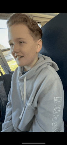 a young boy wearing a light blue hoodie with the word puma on the sleeves