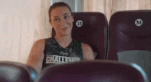 a woman is sitting in a row of purple seats on an airplane .