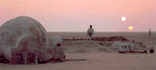 a man stands in the desert looking at the sun setting